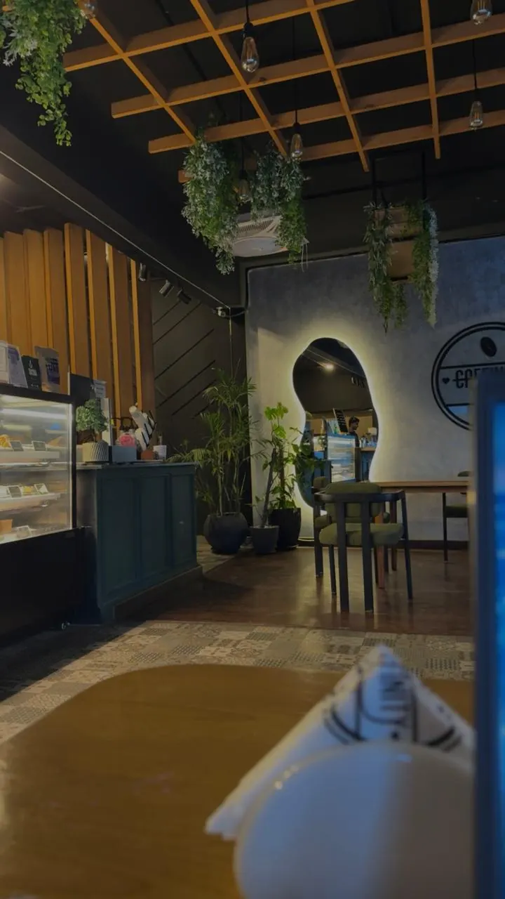 Caffinity's dining room, hanging plants over a glowing mirror and the café's logo