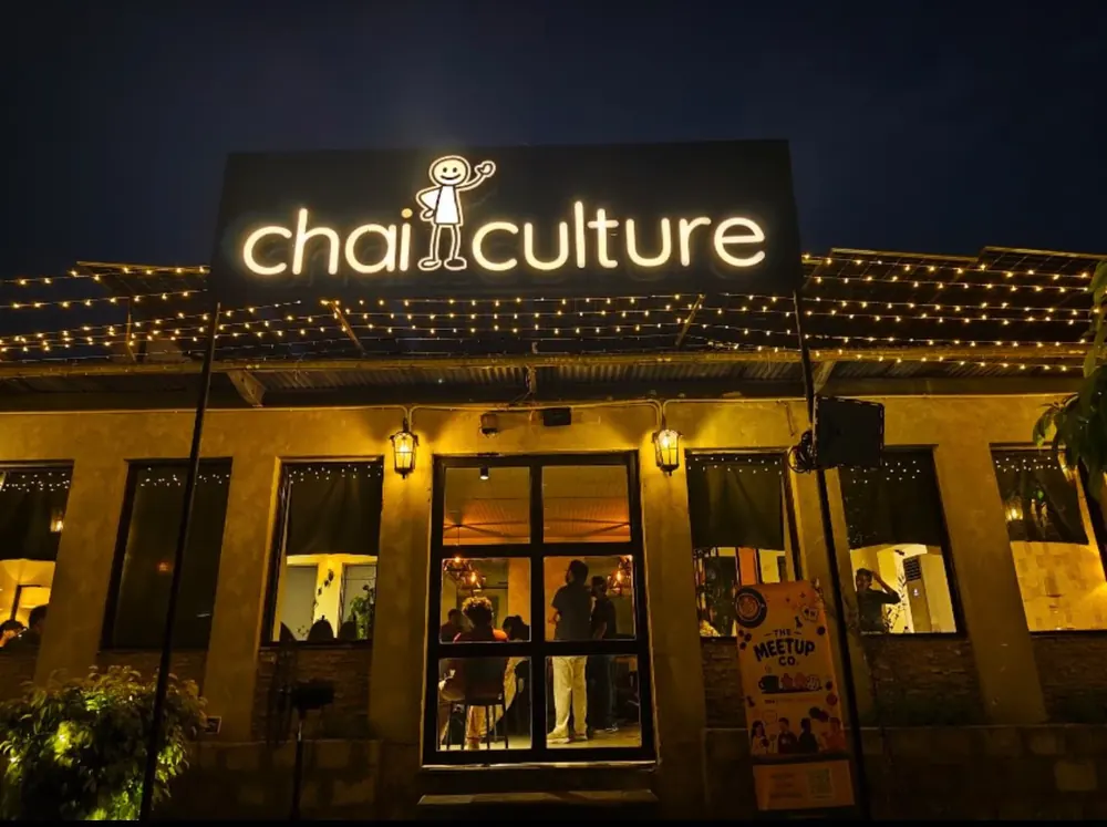 Chai Culture at night, its sign lit and fairy lights along the roof